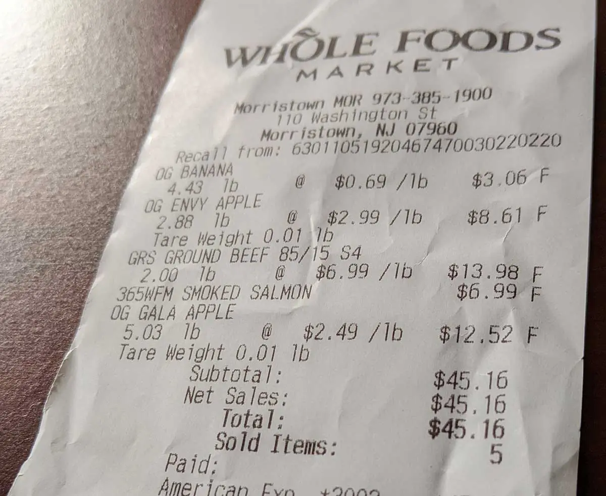 La foto dello scontrino della spesa elenca banane, mele, carne macinata e salmone affumicato ed i rispettivi prezzi