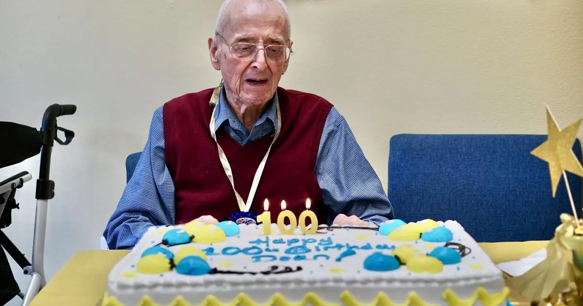 Un vecchietto festeggia cento anni guardando la torta di fronte a lui con le candeline