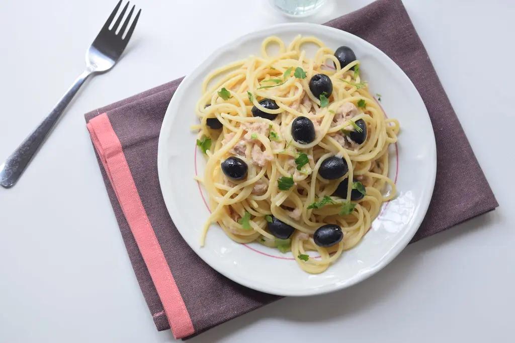 Spaghetti conditi con tonno e olive su un piatto poggiato su un tovagliolo