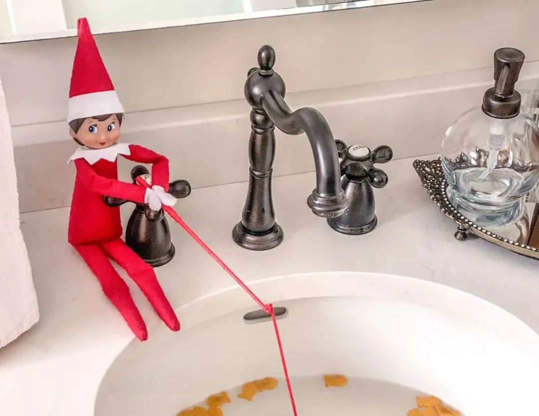 Un piccolo elfo sul lavandino del bagno intento a pescare