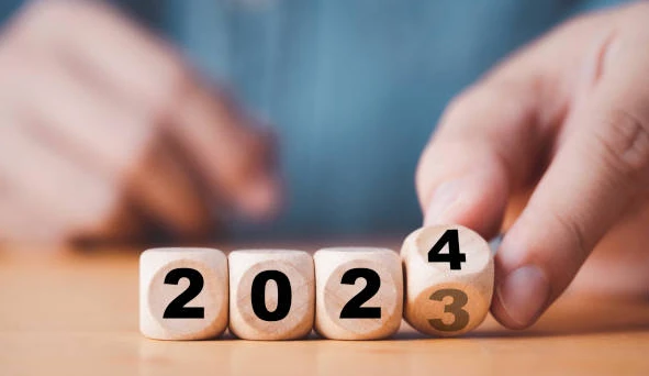 Una mano gira un dado alla fine di una sequenza per cambiare l'anno da 2023 a 2024