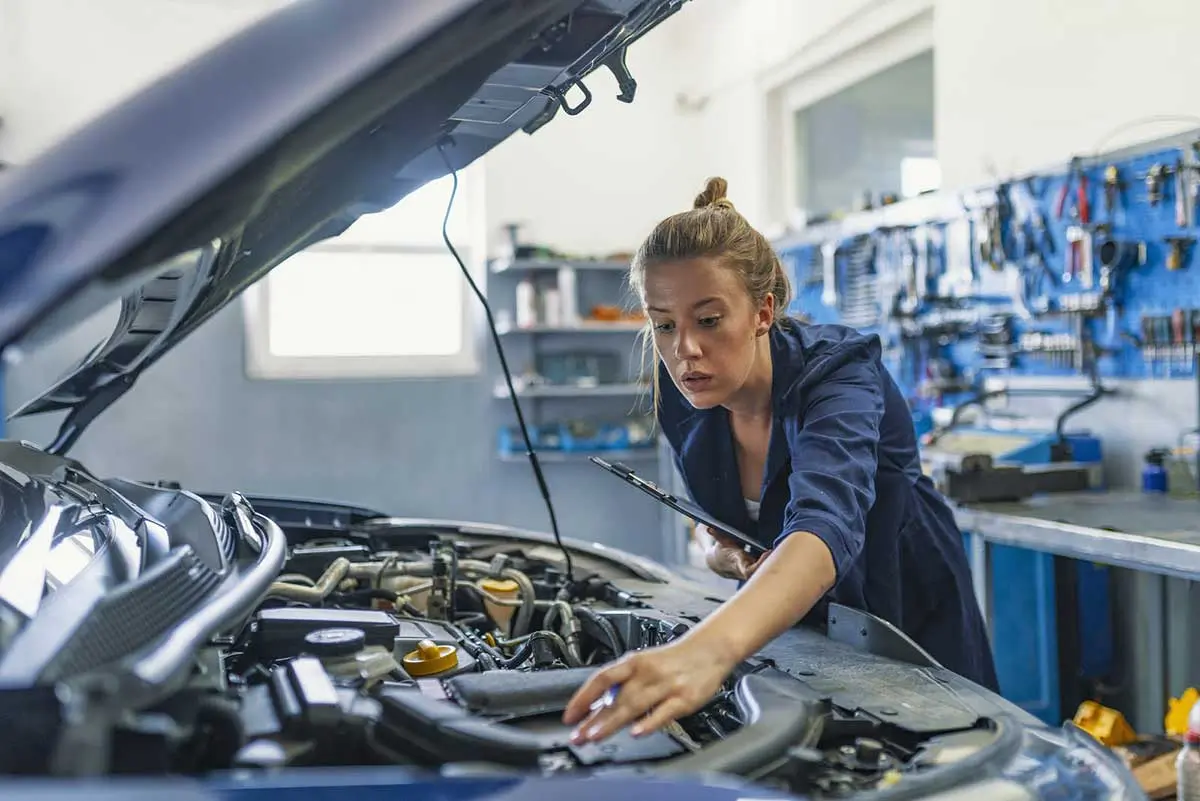 Una donna meccanico controlla il motore di un'autovettura