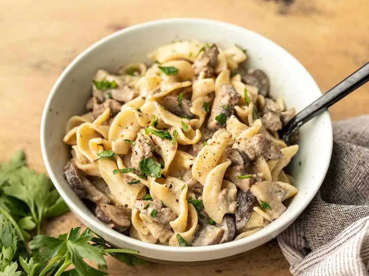 Il risultato finale: pasta all'uovo, carne e funghi in un piatto su un tavolo