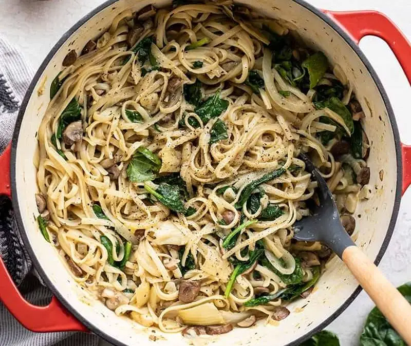 Un piatto con delle tagliatelle condite ed una forchetta pronta a raccoglierle