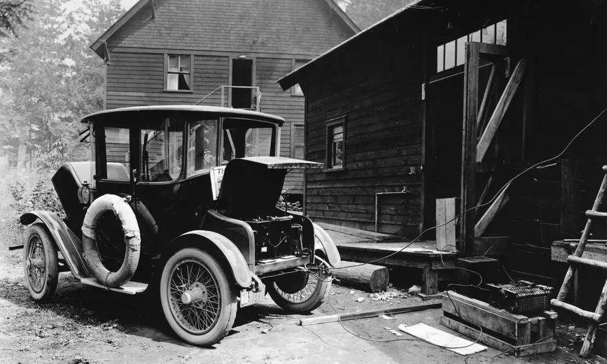 Auto della Detroit Elettric che si ricarica vicino ad un'abitazione