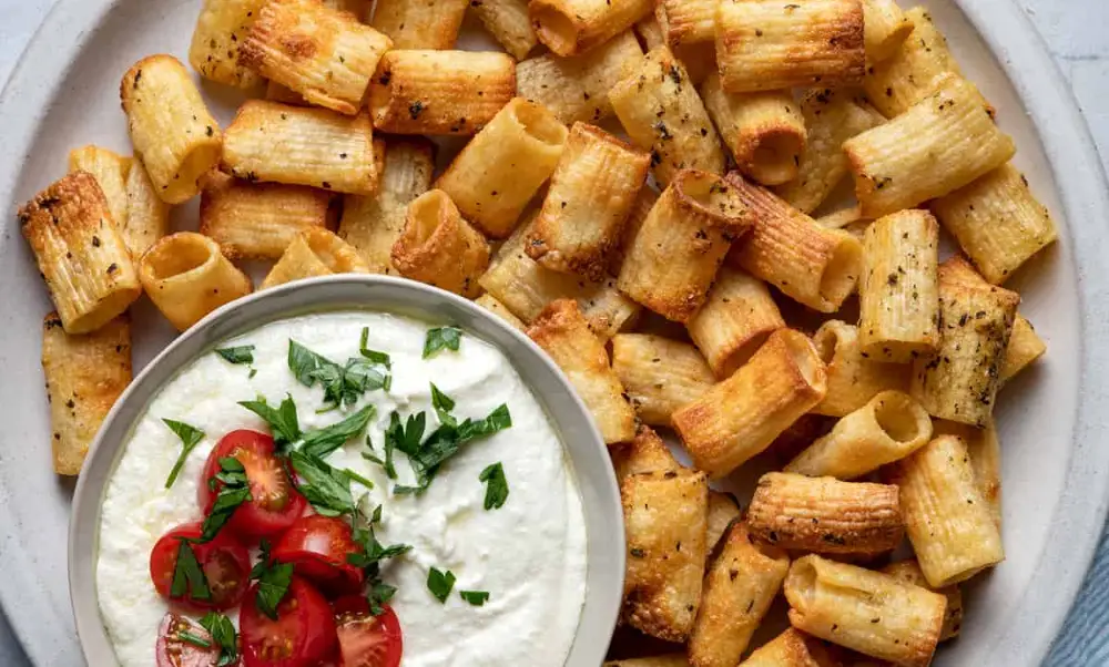 Un piatto di rigatoni cotti nella friggitrice ad aria, con un contorno di panna acida