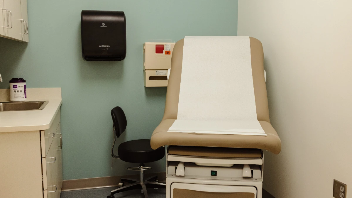 Un tipico studio medico, con lettino, ed un mobile con cassetti dove riporre gli attrezzi