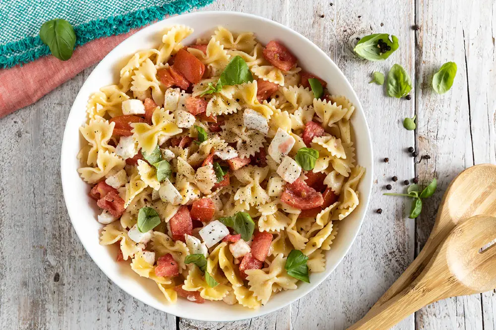 Un piatto pieno di pasta fredda su un tavolo di legno