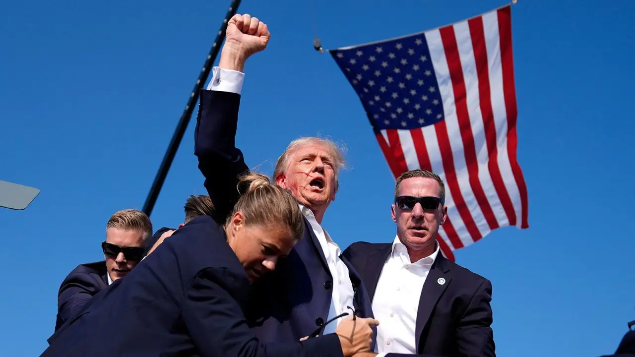 Il presidente Trump con il volto insanguinato protetto dai servizi segreti dopo l'attentato