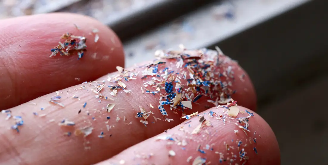 Frammenti di microplastica sulle dita di una mano