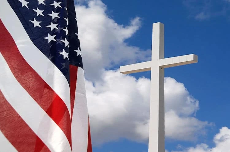 Una bandiera americana vicino ad una croce di cemento