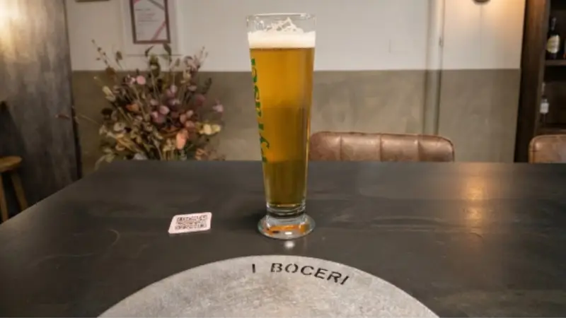 Un bicchiere di birra ed il sottopiatto con scritto I Boceri
